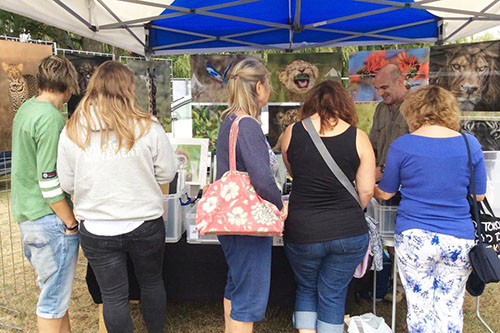 group of people looking through photographer Ashley Vincent’s wildlife prints at an outdoor event