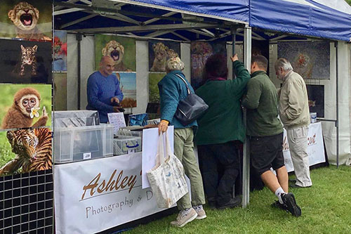 people engaging with Ashley Vincent at his picture display stand at Tenterden