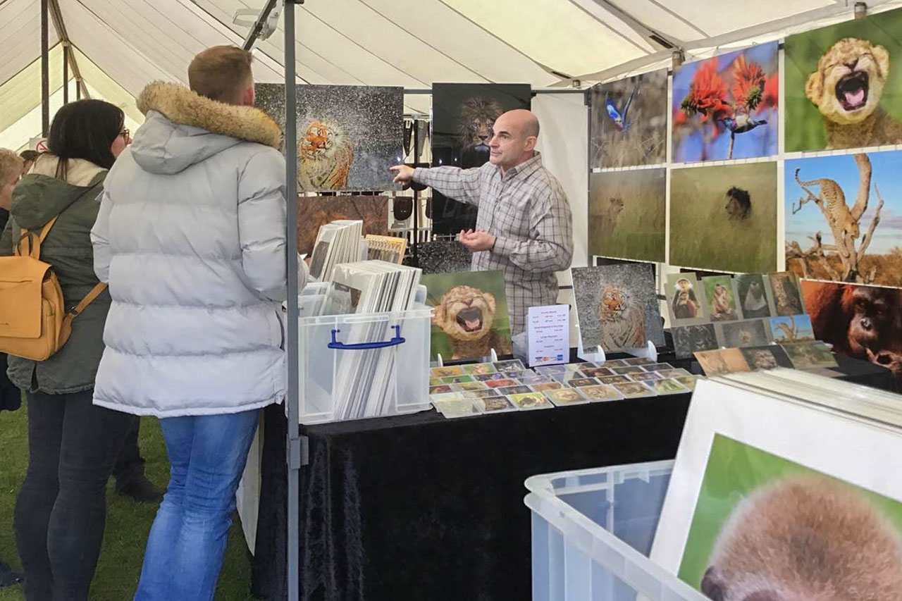 people engaging with Ashley Vincent at his picture display stand at the Cambridge county show