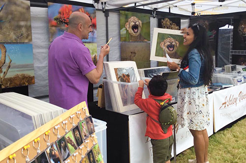 mother and child engaging with Ashley Vincent at his picture display stand at the Thai festival in Manchester