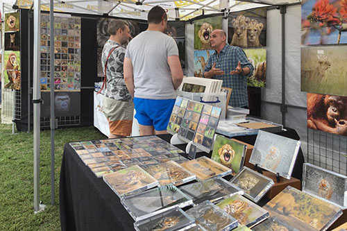 customers engaging with Ashley Vincent at his picture display stand at the Cambridge Thai Festival