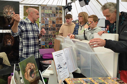 customers engaging with Ashley Vincent at his picture display stand at the Knebworth House