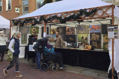 customers engaging with Ashley Vincent at his picture display gazebo at the Chichester Christmas Market