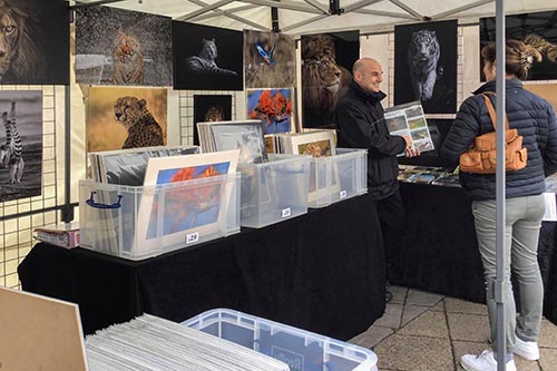 customer engaging with Ashley Vincent at his picture display gazebo at the St Ives spring market